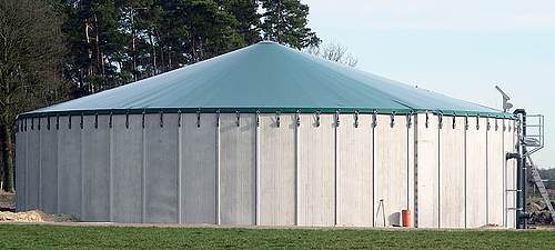 Large Biogas Storage Tank with Green Cover by Huesker Concrete biogas storage tank with green weatherproof cover in a rural field