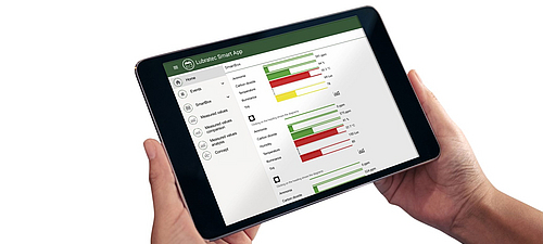 Clear barn climate dashboard in the Lubratec SmartApp Person holding tablet with Lubratec SmartApp launched, on which a clear dashboard for the barn climate can be seen