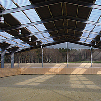 Black Lubratec windbreak net on riding arena gable