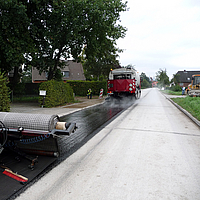 A term machine drives ahead, followed by the application of SamiGrid® asphalt reinforcement on the road