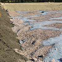 Basetrac Grid geogrid on a construction site, over which sand or gravel has already been partially distributed