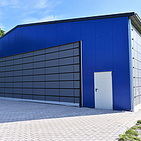 Gray folding front on the gable end of a blue sports hall