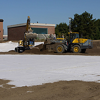 Bulldozer and excavator spread soil over laid Tektoseal® Clay bentonite mats