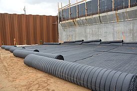 Unlaid rolls of Fortrac MDT geogrid on the ground, ready for installation in soils with extreme pH values and hydraulic binders.