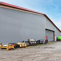 Grey, textile façade cladding including folding front on the front of a machine hall