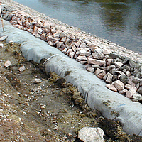 Geotextile nonwoven fabric and stones at water edge for bank protection