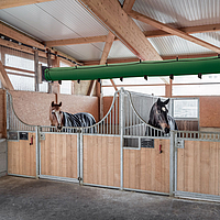 Lubratec Tube Cool on the ceiling of a horse stable and above two horse stalls with horses