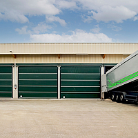 Four green gates at a hall. A lorry with material is sleeping at one of the gates