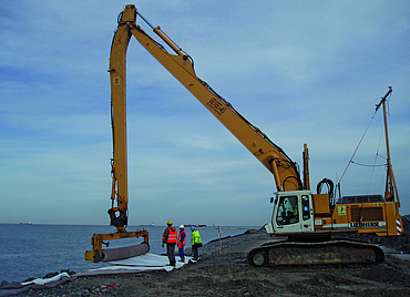 Excavators and workers are laying Tektoseal sand.