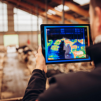 A person uses a thermal imaging camera to inspect a cowshed with reference to Lubratec SmartBox