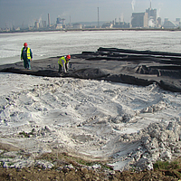 Employees laying Basetrac® Woven film along a body of water