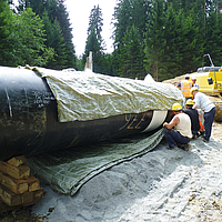 Workers attach the Incomat® Pipeline Cover to the pipe section